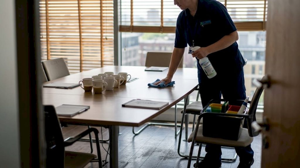 Cleaner sanitizing office table with supplies